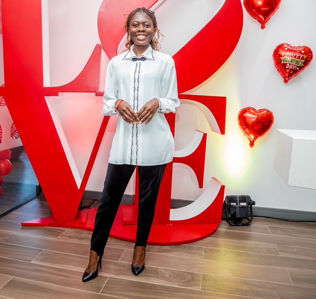 A woman standing in front of giant red 3D letters spelling "LOVE" at a corporate Valentine's Day event.