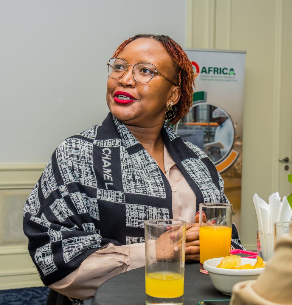 Candid shot of a smiling female executive wearing glasses and a patterned shawl at a JBQ Africa corporate event.