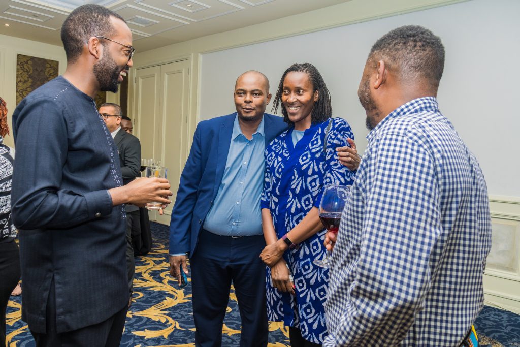A group of four professionals laughing and enjoying a lively networking conversation at a JBQ Africa corporate event in Nairobi.