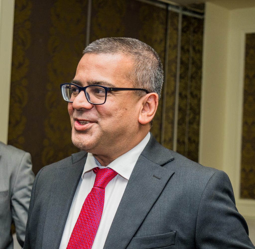 Close-up of a smiling male executive wearing glasses and a red tie at a JBQ Africa corporate event.