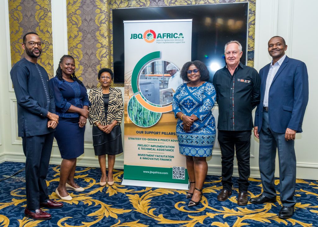 Group of six professionals posing proudly in front of a JBQ Africa banner at a corporate event in Nairobi, Kenya.