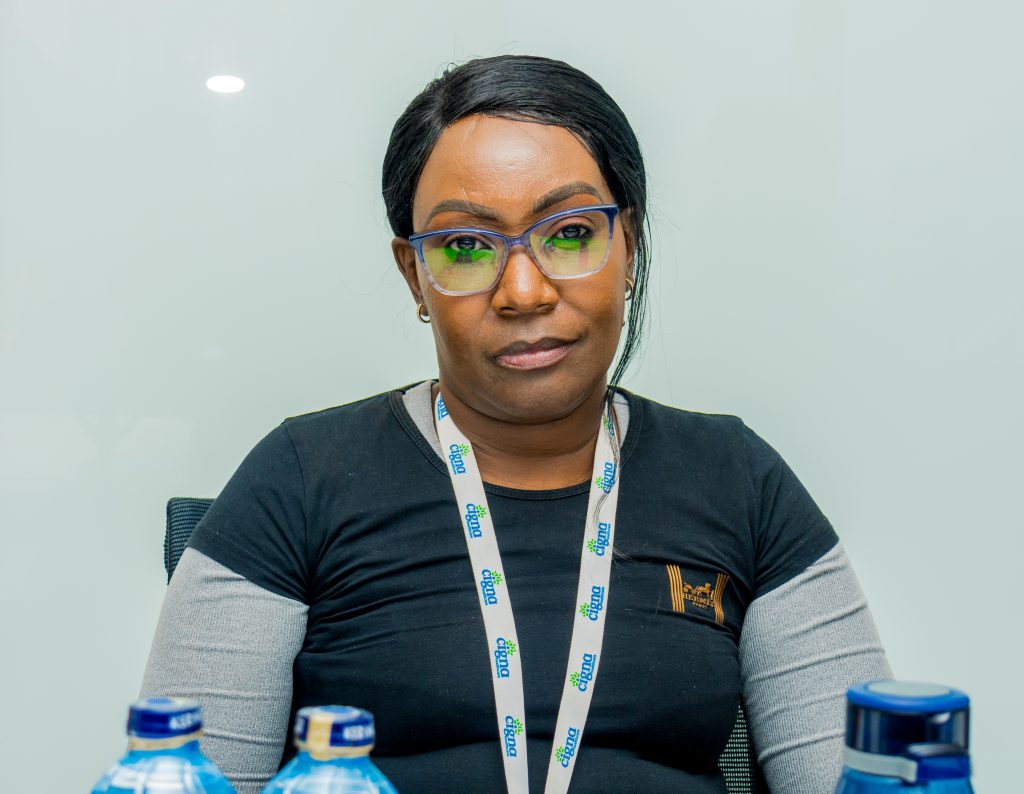 A female employee wearing glasses and a Cigna lanyard sitting at a conference table with water bottles in the foreground.