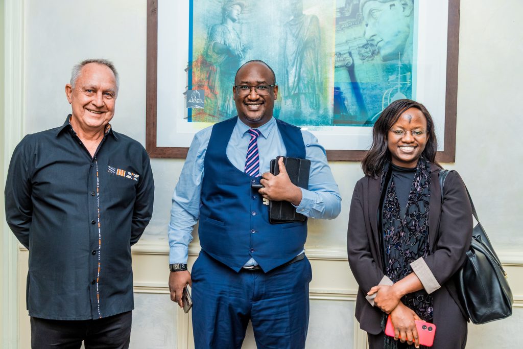 Three professionals smiling for a photo in front of a framed artwork at a JBQ Africa event, photography by Mintglint Media.